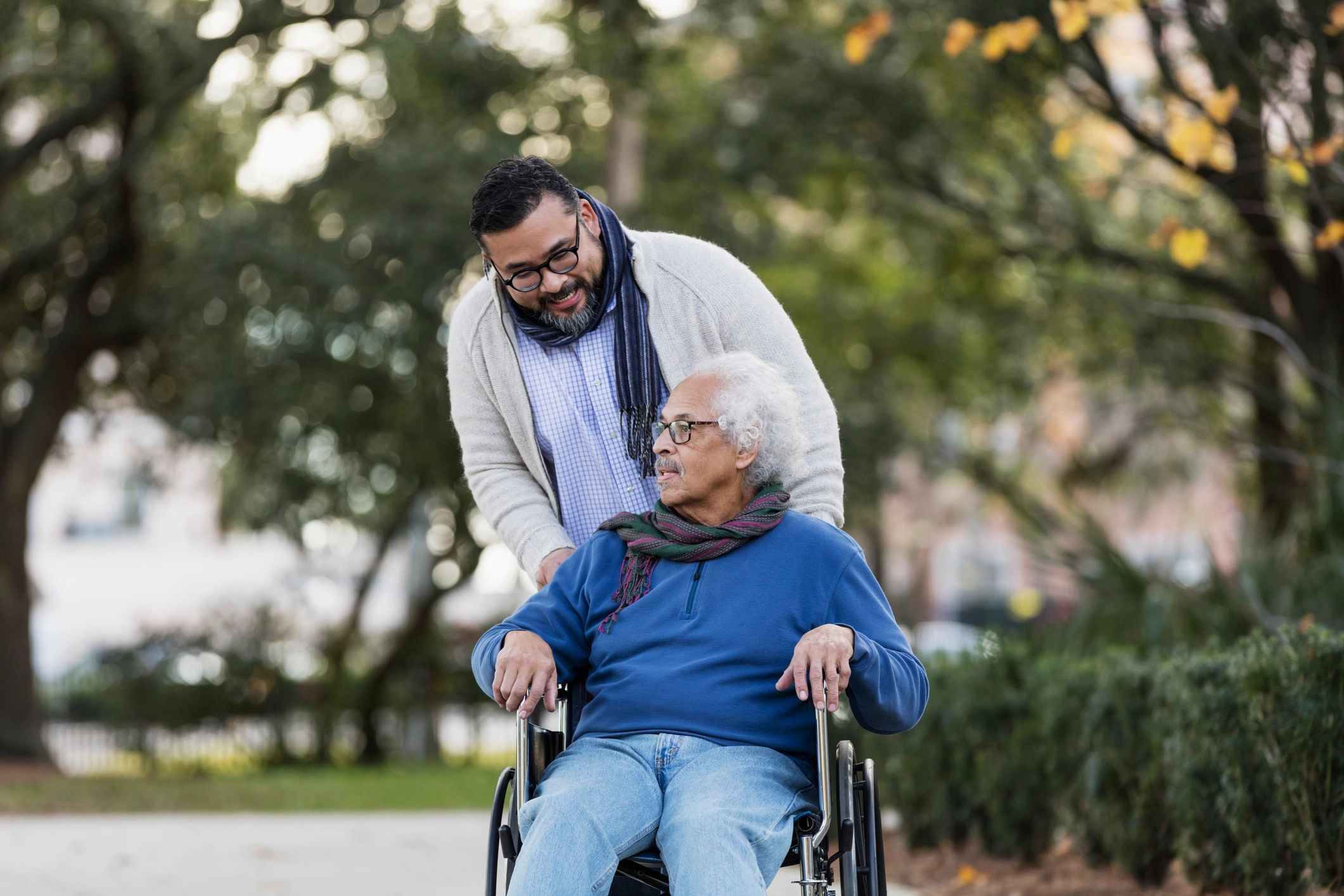 Senior man in wheelchair with family member outdoors