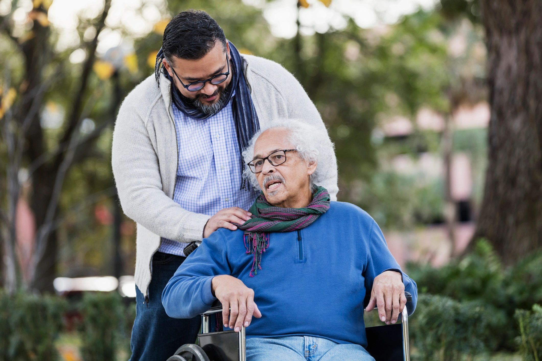 Senior man in a wheelchair outdoors with family support