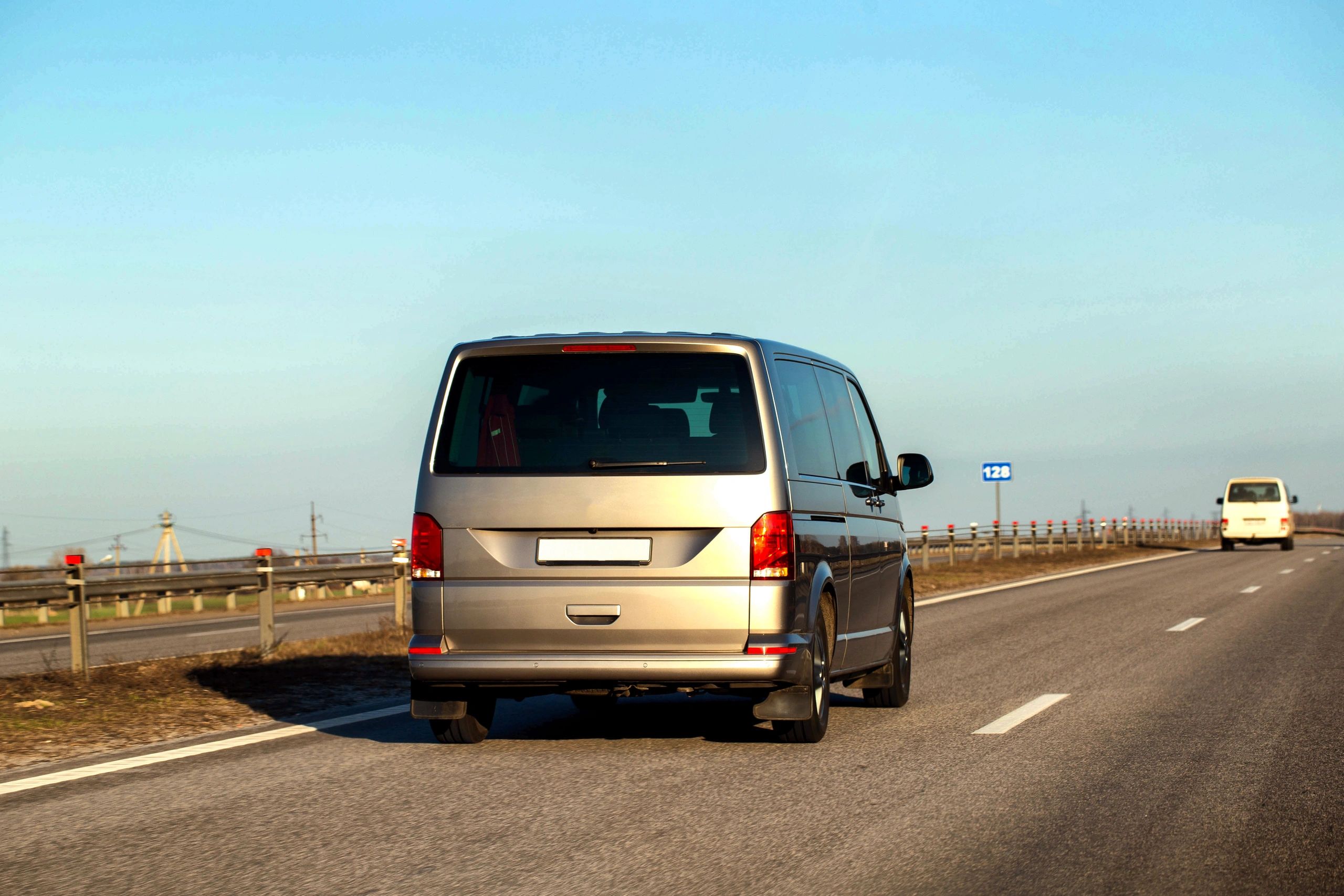 Minivan driving on a highway under a clear sky