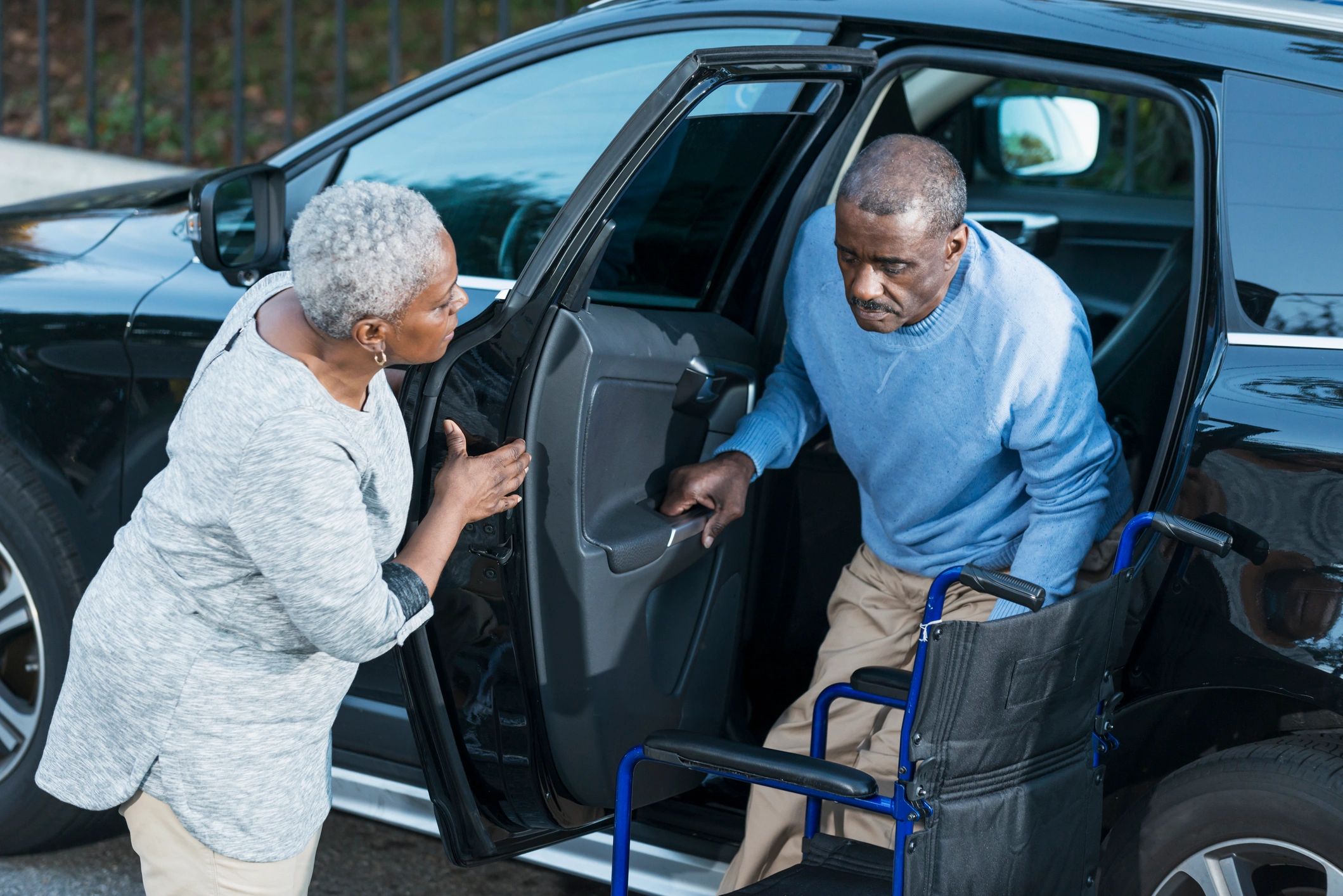 Caregiver assisting a senior out of a car